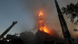Petugas pemadam kebakaran memadamkan gereja La Asuncion setelah diserang dan dibakar saat puluhan ribu orang berunjuk rasa di Kota Santiago, Chile, Minggu (18/10/2020). Demonstrasi itu digelar untuk memperingati satu tahun protes besar menuntut kesetaraan di Chile. (AP Photo/Esteban Felix)