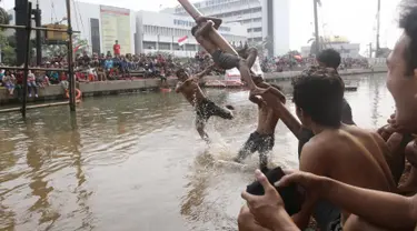Seorang peserta terjatuh saat mengikuti lomba panjat pinang dalam Festival Kalimalang di Cipinang Melayu, Jakarta Timur, Kamis (17/8). Festival Kalimalang ini dalam rangka memeriahkan HUT ke-72 RI. (Liputan6.com/Herman Zakharia)