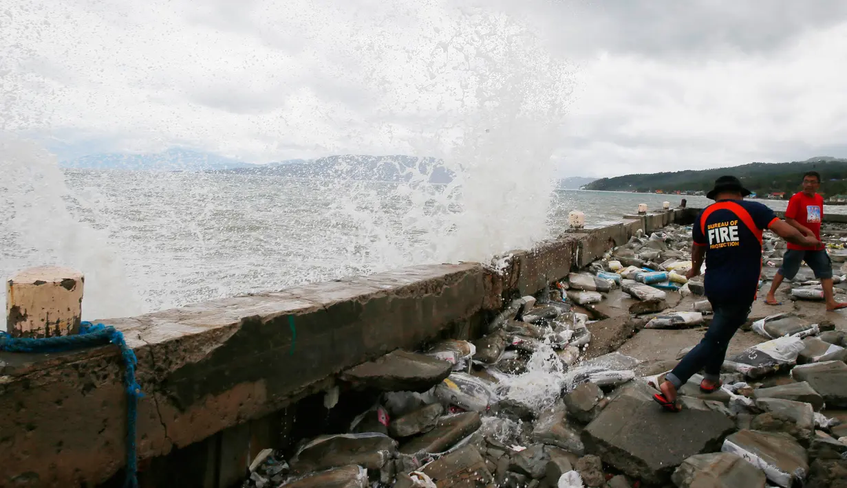 Petugas pemadam kebakaran dan warga menghindar dari hantaman ombak yang disebabkan oleh topan Nock-Ten di Mabini kota, provinsi Batangas selatan Manila, Filipina, (26/12). (AP Photo/Bullit Marquez)