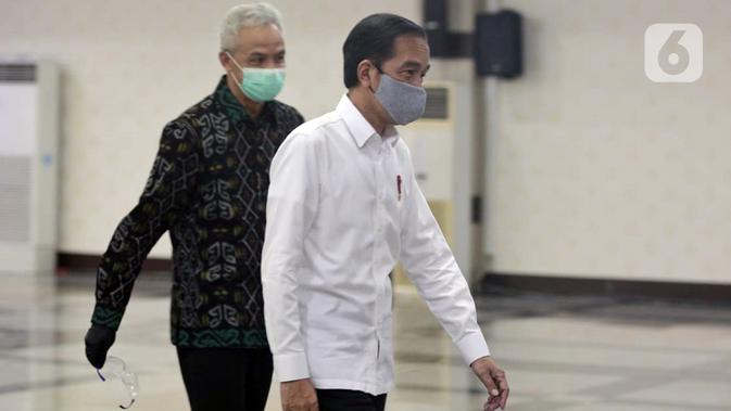 Presiden Joko Widodo atau Jokowi didampingi Gubernur Jawa Tengah Ganjar Pranowo berjalan bersama di Gedung Gradhika Bhakti Praja, Kompleks Kantor Gubernur Jawa Tengah, Semarang, Selasa (30/6/2020). Jokowi melakukan kunjungan kerja ke beberapa wilayah di Jawa Tengah. (Liputan6.com/Gholib)