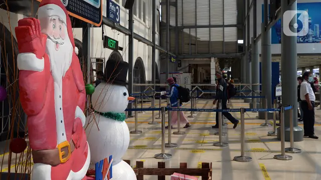 FOTO: Petugas KAI Berkostum Natal Bagikan Masker ke Calon Penumpang di Stasiun Senen
