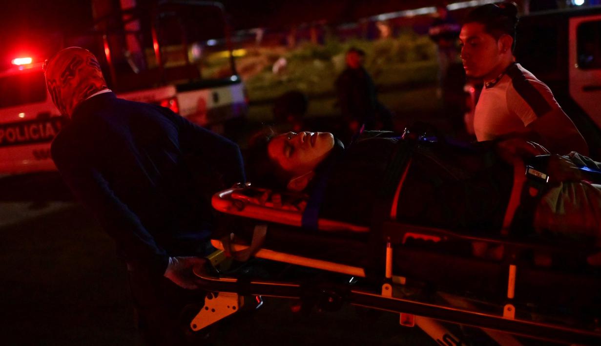 Pekerja darurat membawa orang yang terluka dengan tandu setelah jembatan layang untuk kereta metro ambruk di Mexico City, Senin (3/5/2021). Rel layang tersebut ambruk saat kereta sedang melintas dan menimpa mobil-mobil di jalan di bawahnya. (Pedro PARDO/AFP)