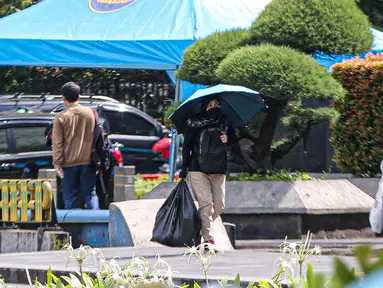 Warga menggunakan payung untuk menghidari paparan sinar matahari saat jalan di kawasan Bundara Hi, Jakarta, Jumat (14/4/2023). (Liputan6.com/Faizal  Fanani)