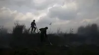 Dua anggota TNI memadamkan api di perkebunan kelapa sawit di Desa Padamaran, Ogan Komering Ilir , Sumatera Selatan, Sabtu (12/9/2015). Kebakaran lahan menyebabkan kabut asap di sejumlah wilayah dan mengganggu jadwal penerbangan. (REUTERS/Beawiharta)