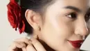 Kecantikannya makin paripurna dengan pernak-pernik simpel tapi memikat. Rona merah terpancar dari bibir dan sanggul mawar di rambutnya. [Instagram/arieltatum]