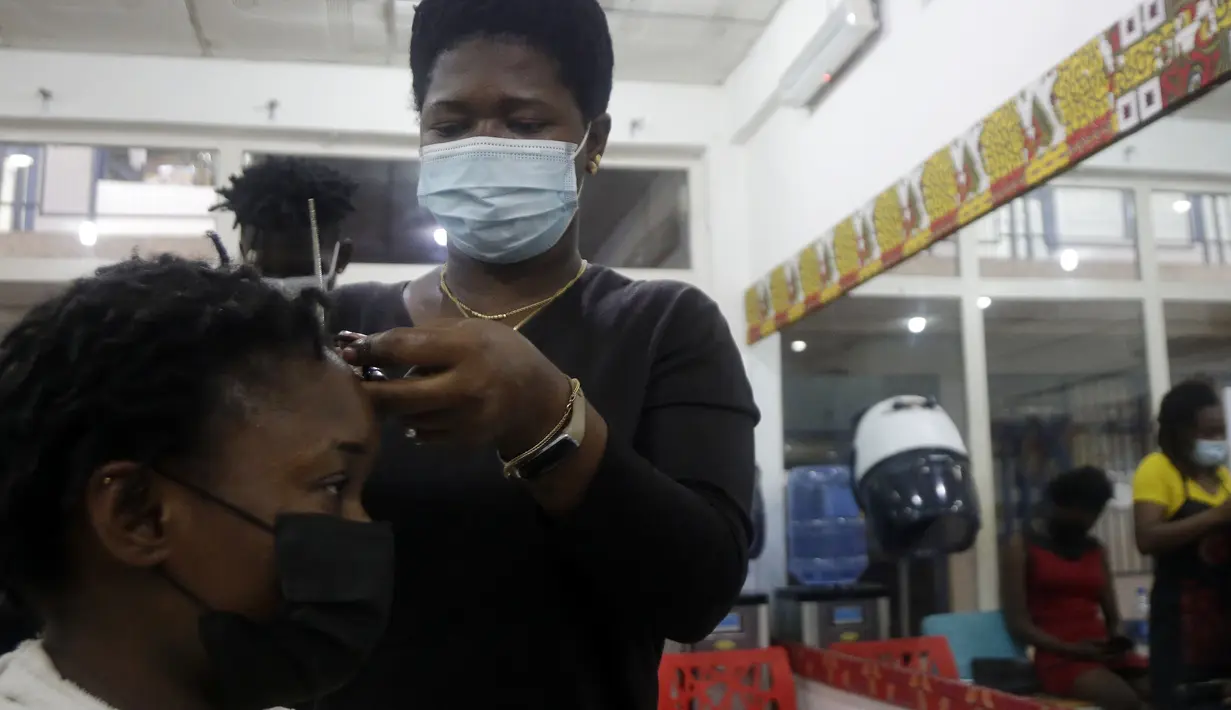 Penata rambut, memakai masker menata rambut pelanggan di dalam salon di Lagos, Nigeria, Rabu (26/5/2021). Salon tersebut menerapkan protokol kesehatan untuk para penata rambutnya saat melayani pelanggan untuk menghindari penyebaran virus Covid-19. (AP Photo/Sunday Alamba)