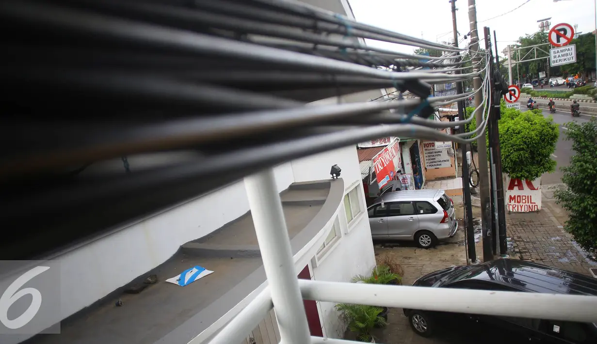 Kabel dari tiang listrik yang melintasi dan menjuntai di JPO kawasan Cawang, Jakarta, Rabu (25/1). Selain mengganggu kenyamanan, buruknya penempatan instalasi kabel tersebut juga berbahaya bagi keselamatan pengguna JPO. (Liputan6.com/Immanuel Antonius)