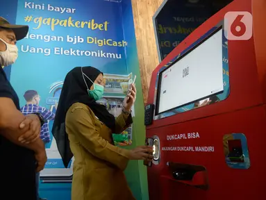 Petugas membantu warga yang akan melakukan pencetakan di mesin Anjungan Dukcapil Mandiri (ADM) di Pamulang Square, Tangerang Selatan, Senin (15/9/2020). Pemkot Tangsel memudahkan pelayanan kependudukan untuk membuat KTP El, Kartu Identitas Anak dan Kartu Keluarga. (merdeka.com/Dwi Narwoko)