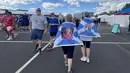 Suporter Skotlandia berjalan di area fanzone Gillette Stadium, Foxborough, Amerika Serikat, Jumat (19/6/2026), menjelang laga melawan Maroko pada Piala Dunia 2026. Mereka mengenakan jubah bergambar dan bendera Saltire sebagai bentuk dukungan sekaligus penghormatan kepada sesama anggota Tartan Army. (KLY Sports/Hery Kurniawan)