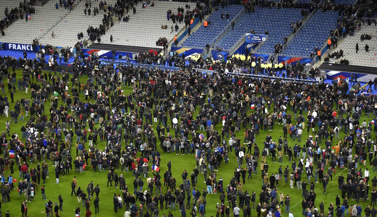 Suporter sepak bola berkumpul di lapangan menunggu izin keamanan untuk meninggalkan Stade de France di Saint-Denis, Paris, (13/11). Dikabarkan ada 140 orang tewas dalam aksi teroris di dekat stadion Stade de France. (AFP PHOTO/FRANCK FIFE)
