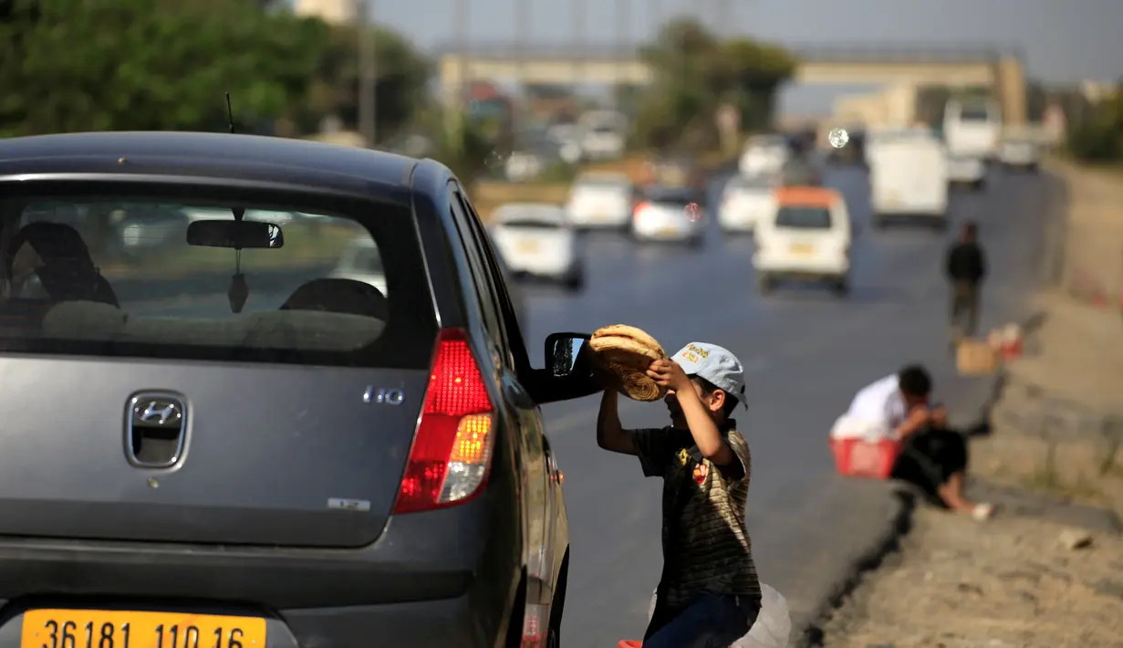 Seorang bocah menawarkan roti tradisional dagangannya kepada pembeli di pinggiran Algiers, Aljazair, 13 Juni 2016. Selama bulan Ramadan, sejumlah anak membantu orangtuanya menjajakan roti di kawasan ini. (REUTERS/Zohra Bensemra)
