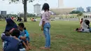 Sejumlah pengunjung beristirahat di rumput selama liburan di Monumen Nasional (monas), Jakarta, Selasa (25/12). Liburan Natal 2018, banyak warga datang bersama kerabat maupun keluarga memadati Monas. (Liputan6.com/Herman Zakharia)