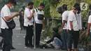Polisi berpakaian kaus putih memeriksa seorang anak muda yang dicurigai terlibat kericuhan di kawasan Tugu Tani, Jakarta, Selasa (13/10/2020). Sejumlah pemuda diamankan polisi karena dicurigai terlibat kericuhan di kawasan Tugu Tani. (Liputan6.com/Helmi Fithriansyah)