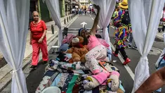 Seorang wanita Kolombia berbaring di tempat tidur saat ambil bagian dalam pawai merayakan Hari Kemalasan Sedunia di Itagui, dekat Medellin, Minggu (19/8). Upaya unik itu untuk medesak para perkerja yang tertekan agar bersantai. (AFP/JOAQUIN SARMIENTO)