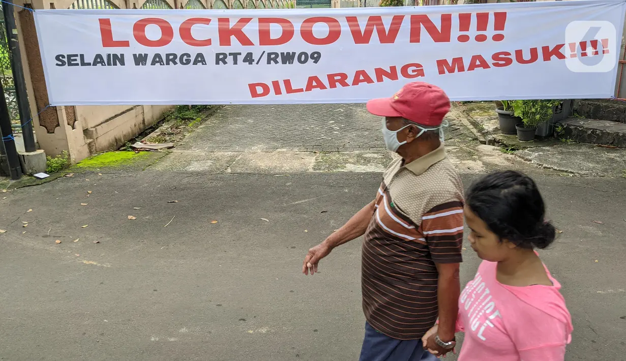 Pejalan kaki melintas di depan spanduk pemberitahuan lockdown di RT 04 / RW 09 Kelurahan Pondok Karya, Tangerang Selatan, Rabu (23/6). Melonjaknya kasus covid-19 di beberapa kawasan membuat sejumlah wilayah melakukan karantina di tingkat RT untuk memutus penyebaran corona (Liputan6.com/Angga Yuniar)