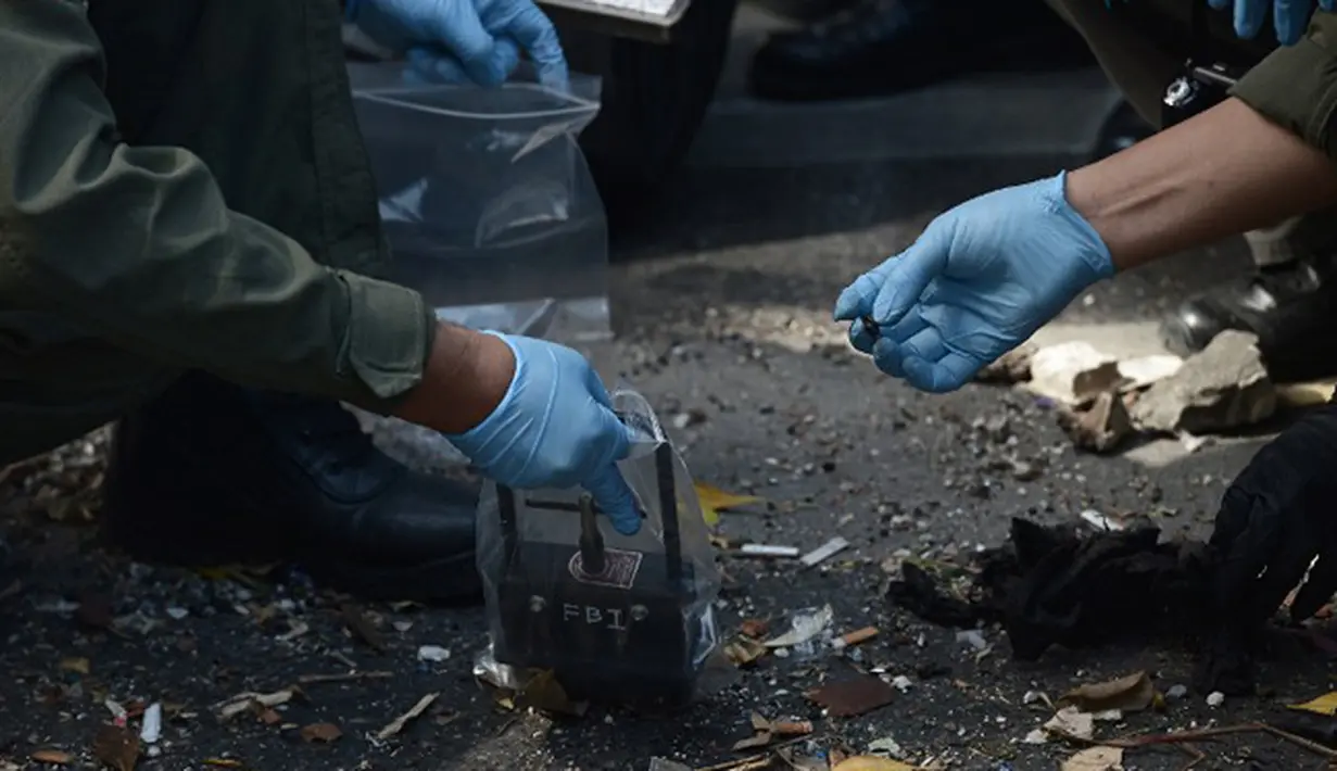 Petugas kepolisian Thailand menggunakan peralatan magnetik saat menyisir puing-puing di depan kuil Erawan, Bangkok, Thailand, (18/8/2015). Ledakan bom tersebut menewaskan 22 orang. (AFP PHOTO/Christophe ARCHAMBAULT )
