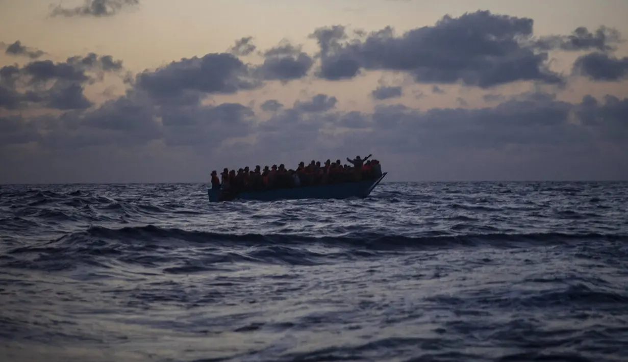 Imigran menunggu petolongan LSM Spanyol Open Arms di Laut Mediterania, Selasa (8/9/2020). Puluhan imigran termasuk wanita dan anak-anak asal Mesir, Maroko, Somalia, dan Sierra Leone menghabiskan lebih dari 20 jam saat melarikan diri dari Libya dengan kapal kayu. (AP Photo/Santi Palacios)