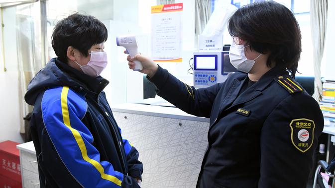 Seorang operator (kanan) mengukur suhu tubuh karyawan di sebuah terminal bus di Beijing, ibu kota China, pada 3 Februari 2020. Senin (3/2) menandai hari pertama masuk kerja setelah libur Tahun Baru Imlek di Beijing di tengah wabah virus corona. (Xinhua/Ren Chao)