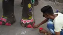 Seorang pria melukis kaki gajah menjelang festival Hindu tahunan Rath Yatra di Ahmedabad, India (3/7/2019). Aktivis hak-hak hewan ingin festival Hindu tahunan Rath Yatra yang melibatkan gajah dihentikan. (AFP Photo/Sam Panthaky)