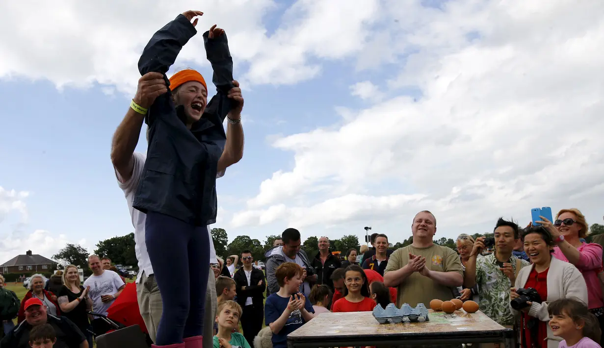 Anya Dawson (8 tahun), mengangkat kedua tangannya usai memenangkan permainan Russian Egg Roulette dalam acara Kompetisi Melempar Telur Dunia dan Vintage Day di Swaton, Inggris, Minggu (28/6/2015). (REUTERS/Darren Staples)