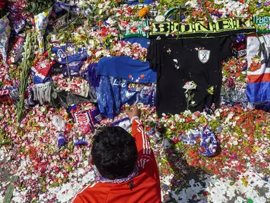 Seorang pria melakukan tabur bunga di luar Stadion Kanjuruhan, Malang, Jawa Timur, Selasa (4/10/2022). Polri menjatuhkan sanksi kepada 10 anggota polisi dan menyelidiki 18 orang lainnya buntut tragedi kerusuhan yang menewaskan 125 orang di Stadion Kanjuruhan. (AP Photo/Dicky Bisinglasi)