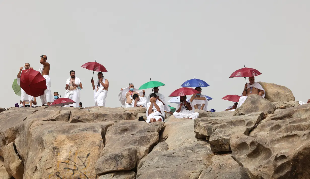 Jemaah haji memanjatkan doa di sekitar Jabal al-Rahma (Gunung Rahmat) saat menunaikan prosesi wukuf di Padang Arafah, tenggara Kota Suci Mekah, Arab Saudi, Senin (19/7/2021). Wukuf di Padang Arafah menjadi puncak ibadah selama prosesi haji. (FAYEZ NURELDINE/AFP)