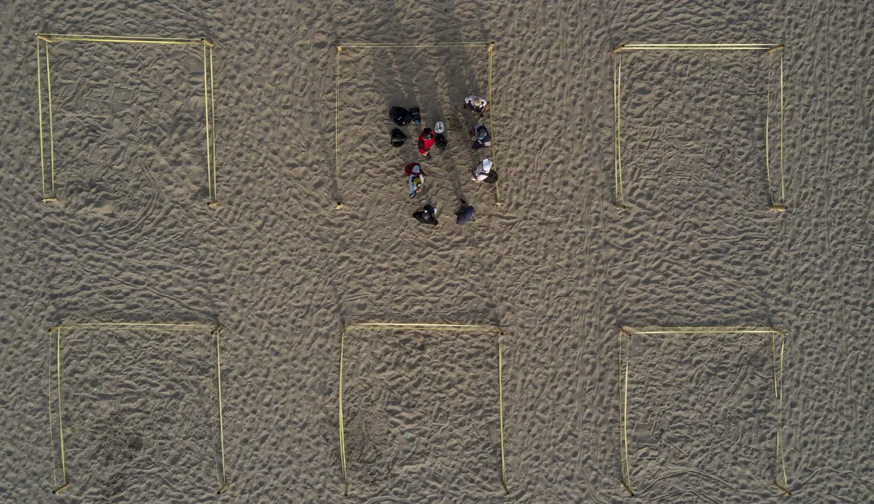 Para pengunjung berjemur dalam pembatas untuk menghindari keramaian di tengah pandemi COVID-19 di Pantai Lima, Peru, Rabu (21/12/2021). Di pantai-pantai populer di Lima, pihak berwenang memutuskan membuat pembatas untuk mencegah kerumunan pengunjung. (Ernesto BENAVIDES/AFP)