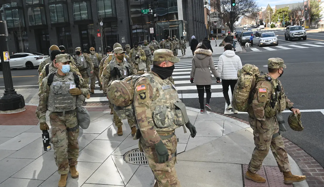 Anggota Garda Nasional menyeberang jalan di Washington, DC, saat pengamanan diperketat pada Senin (18/1/2021). Menurut laporan, 25.000 tentara Garda Nasional akan menjaga kota tersebut sebagai persiapan untuk pelantikan Joe Biden sebagai Presiden ke-46 Amerika Serikat. (Brendan Smialowski/AFP)
