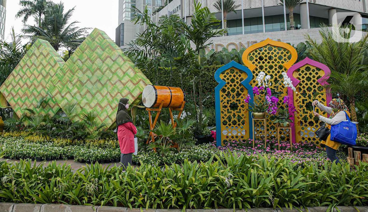<p>Warga berfoto dengan dekorasi bertemakan Idul Fitri di kawasan Bundaran HI, Jakarta, Rabu (27/4/2022). Dekorasi berbentuk masjid, ketupat, dan bedug yang dihiasi oleh tanaman tersebut dalam rangka menyambut Idul Fitri 1443 Hijriah. (Liputan6.com/Faizal Fanani)</p>