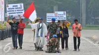 Aksi Anggota Polisi Militer Angkatan Darat IV/Surakarta Kopral Partika Subagyo Lelono (53) di Tugu Monas, Jakarta, Jumat (17/6). Kopral Bagyo juga didampingi beberapa orang sambil membawa atribut bertulisan bahaya narkoba. (Liputan6.com/Gempur M Surya)