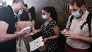 Seorang penonton menunjukkan kartu identitas saat pemeriksaan paspor kesehatan sebelum memasuki bioskop Grand Rex di Paris, Rabu (21/7/2021). Mereka yang pergi ke bioskop, museum atau pertandingan olahraga di Prancis harus membuktikan telah divaksin atau hasil tes negatif Covid-19 (ALAIN JOCARD/AFP)