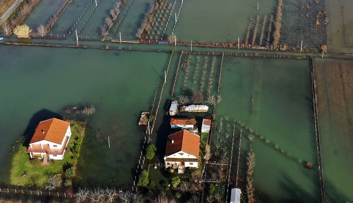 Air hujan membanjiri Desa Obot, sekitar 100 kilometer (60 mil) barat laut Tirana, Albania, Senin (11/1/2021). Pihak berwenang telah mengevakuasi banyak warga menyusul banjir yang merendam ribuan hektare (acre) kawasan di Albania. (AP Photo/Hektor Pustina)