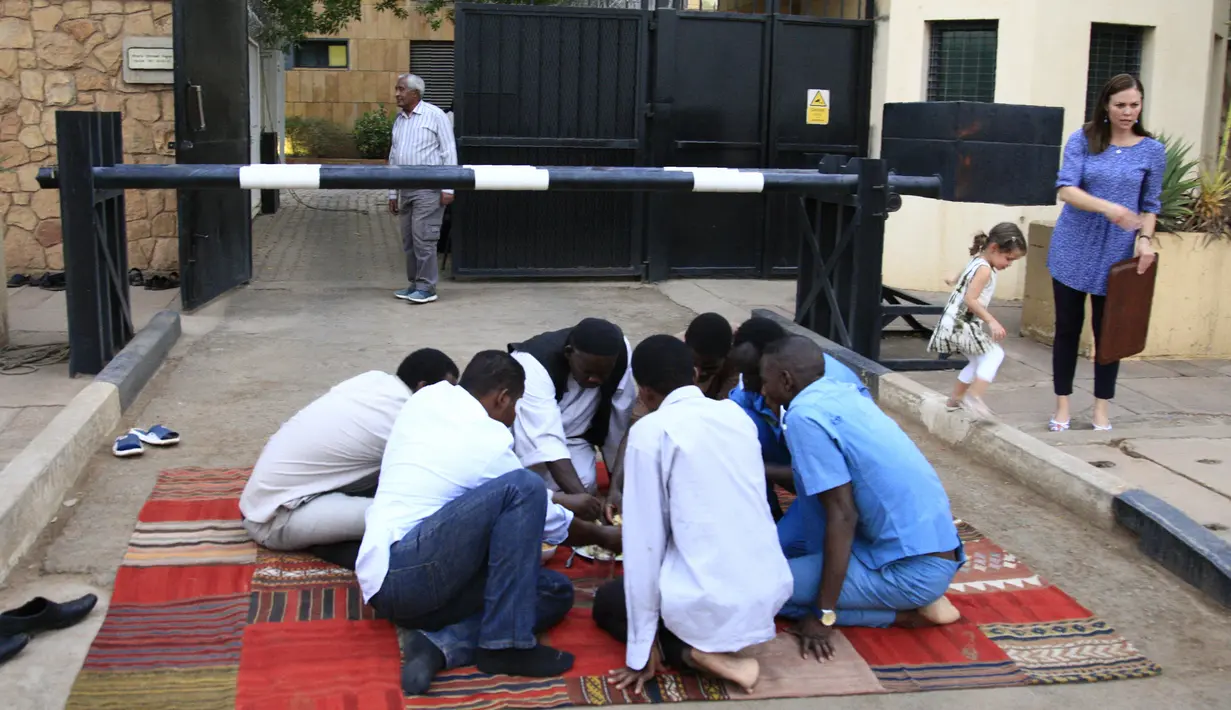 Sejumlah pria Sudan berbuka puasa selama bulan suci Ramadan di depan kedubes Inggris di ibukota Khartoum (23/5/2019). Duta Besar Inggris untuk Sudan, Irfan Sidiq menggelar buka puasa bersama di ibu kota tersebut. (AFP Photo/Ebrahim Hamid)