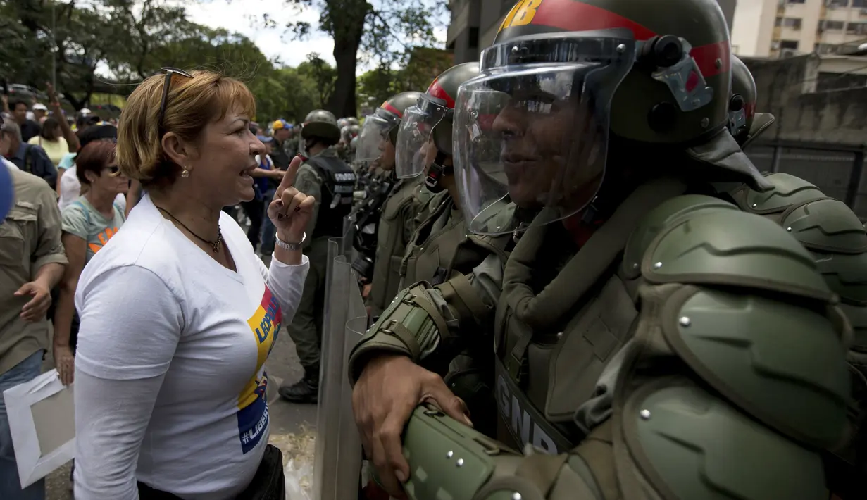Polisi berjaga-jaga saat aksi menolak keputusan Mahkamah Agung  yang mencabut kekuasaan dari Majelis Nasional di Caracas, Venezuela, Sabtu (1/4). MA akhirnya membatalkan putusannya untuk memakzulkan kongres. (AP Photo / Fernando Llano)