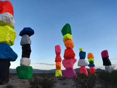 Seorang bocah memandangi instalasi seni yang berjudul ' Seven Magic Mountains' yang dibuat oleh seniman Swiss Ugo Rondinone di dekat Jean , Nevada, 14 Mei 2016. Karya seni berupa menara yang terbentuk dari tumpukan batu yang indah. (David Becker / AFP)