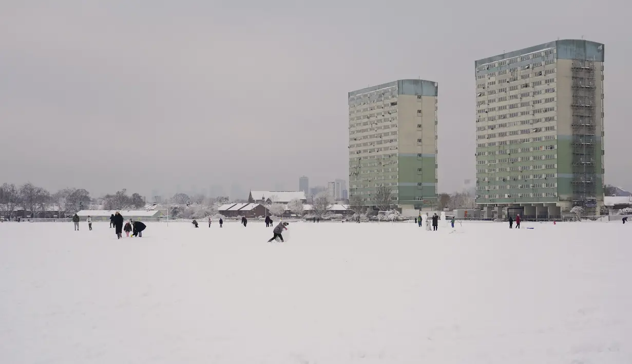 Orang-orang berjalan di salju yang menutupi Wanstead Flats, di London, Senin (10/12/2022). Salju dan es telah menyapu sebagian Inggris, dengan suhu dingin dan kabut yang membekukan serta salju diperkirakan akan tetap ada sepanjang minggu ini. (AP Photo/Alberto Pezzali)