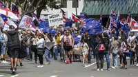 Demonstran berbaris di sepanjang Lambton Quay sebelum berkumpul di gedung Parlemen Selandia Baru, di Wellington, Selasa (9/11/2021). Ribuan warga Selandia Baru berdemonstrasi memprotes kebijakan vaksin covid-19 dan penguncian (lockdown) yang diterapkan negara itu. (Mark Mitchell/NZ Herald via AP)