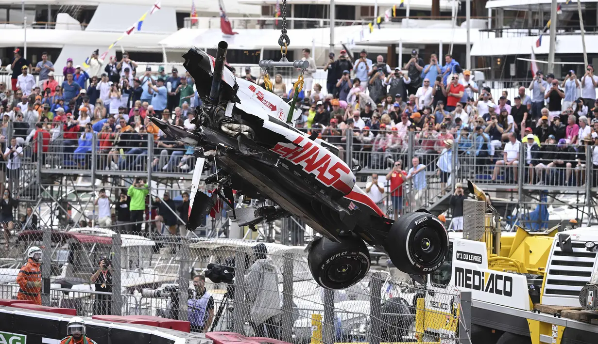 Sejumlah marshall berusaha mengevakuasi mobil pembalap Haas, Mick Schumacher usai mengalami kecelakaan saat Formula 1 GP Monako yang berlangsung di Circuit de Monaco, Minggu, 29 Mei 2022. (AP/Pool/Christian Bruna)