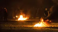 Para pengunjuk rasa berada di balik barikade yang terbakar saat bentrok dengan polisi di Tunisia (9/1/2018). (AP Photo/Amine Landoulsi)