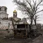 Seorang wanita dengan sepeda&nbsp;melewati kendaraan yang terbakar, di depan Gereja yang rusak di Lukashivka, dekat kota Chernihiv di Ukraina utara, 22 April 2022. Penduduk mengatakan tentara Rusia menggunakan rumah ibadah untuk menyimpan amunisi, dan pasukan Ukraina menembaki gedung itu untuk membuat Rusia pergi. (AP Photo/Petros Giannakouris)