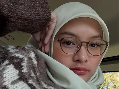 Pilihan hijab polos berwarna pastel terlihat serasi dengan wajahnya yang cantik natural. Aisha juga memadukannya dengan busana bermotif dan kacamata bergaya klasik yang menambah kesan cerdas sekaligus feminin. Penampilan ini memberikan kesan matang, tetapi tetap memancarkan aura imut khas remaja. (Liputan6.com/IG/@khadeejaisha)