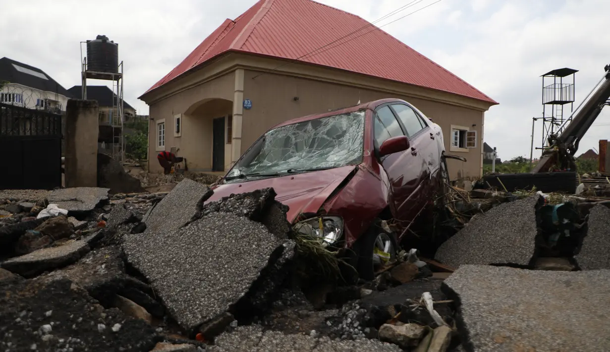 Sebuah mobil terlihat di jalan yang terkena banjir bandang setelah hujan deras di Trademoore Estate, Lugbe, Abuja, Nigeria (13/9/2021). Badan Manajemen Darurat Nasional Nigeria (NEMA) mengkonfirmasi 3 orang tewas, dan puluhan mobil dan rumah terkena dampak di malapetaka. (AFP/Kola Sulaimon)