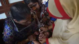 Seorang anak menangis saat diberikan vaksin polio selama kampanye vaksinasi polio di Karachi, Pakistan (9/4). Pakistan adalah salah satu dari hanya dua negara di dunia di mana polio, penyakit masa kecil yang melumpuhkan. (AFP Photo/Rizwan Tabassum)