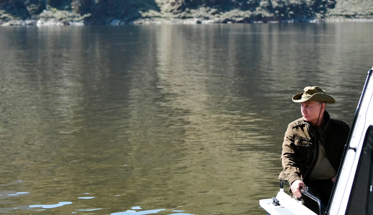 Dalam foto yang diambil pada  25 Agustus 2018, memperlihatkan Presiden Rusia Vladimir Putin duduk di atas sebuah perahu di sungai Yenisey selama liburan singkatnya di Tuva daerah terpencil di Siberia selatan. (Alexei Nikolsky/Sputnik, Kremlin Pool via AP)
