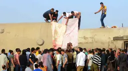 Orang-orang berkumpul di lokasi kecelakaan kereta penumpang dekat Banha, Provinsi Qalyubia, Mesir, Minggu (18/4/2021). Ratusan penumpang memanjat keluar kereta yang terbalik sesaat setelah kecelakaan. (AP Photo/Tarek Wagih)