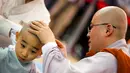 Seorang biksu Budha mencukur kepala seorang biksu pemula saat upacara pemberkatan Biksu di kuil Jogye, Seoul, Senin (11/5/2015). Sepuluh orang anak diberikan kesempatan untuk mengalami kehidupan sebagai biksu selama dua minggu. (REUTERS/Thomas Peter)