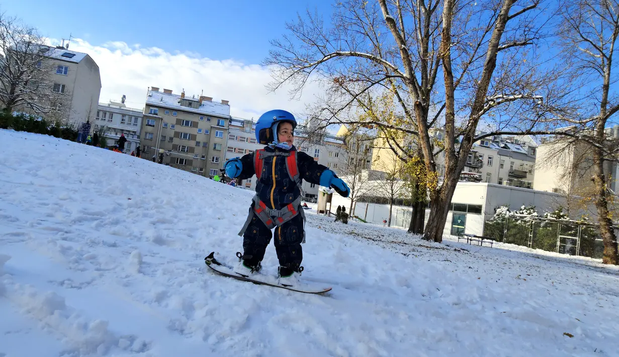 Seorang anak laki-laki berusia dua tahun bermain papan seluncur salju di taman Steinhage di Wina, Austria pada 3 Desember 2023. (Joe Klamar / AFP)