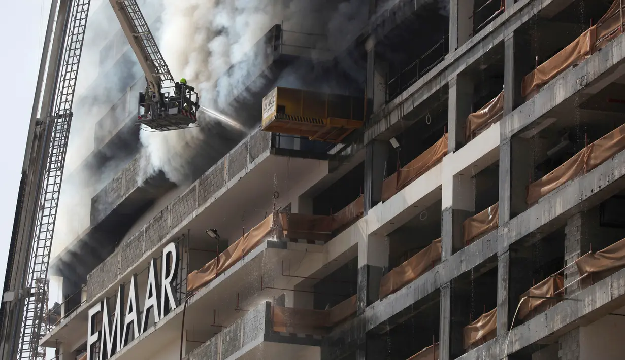 Petugas memadamkan api yang melanda sebuah gedung di sebelah Dubai Mall, Uni Emirat Arab, Minggu (2/4). Gedung yang terbakar diketahui sedang dikerjakan raksasa kontruksi Emaar. (AP Photo/ Jon Gambrell)