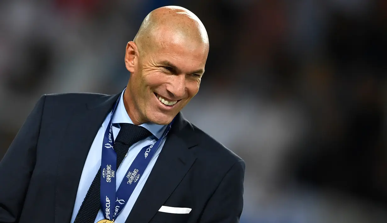 Zinedine Zidane tersenyum dengan medali usai memenangkan pertandingan melawan Manchester United di Arena Philip II di Skopje (8/8). Trofi Piala Super Eropa 2017 adalah trofi keenam yang dipersembahkan Zidane untuk Real Madrid. (AFP Photo/Dimitar Dikloff)