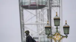 Seorang pejalan kaki berjalan di atas Jembatan Westminster di London, Senin (10/1/2022). Penasihat pemerintah Inggris telah merekomendasikan untuk tidak memberikan dosis keempat vasksin Covid-19 bagi kelompok usia di atas 80 tahun atau lansia. (AP Photo/Kirsty Wigglesworth)